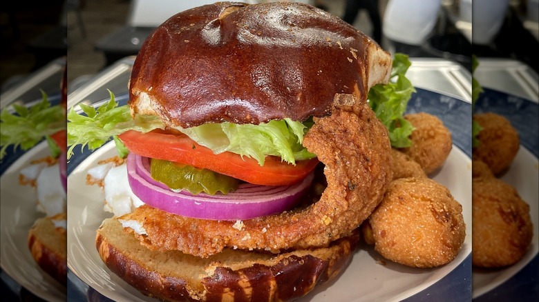 Fried fish sandwich on potato bun with hushpuppies on side