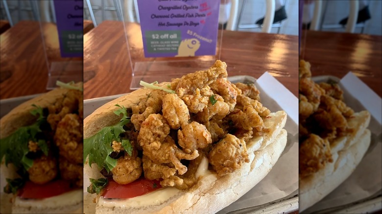 Fried crawfish Po'boy sandwich on wooden table at restaurant