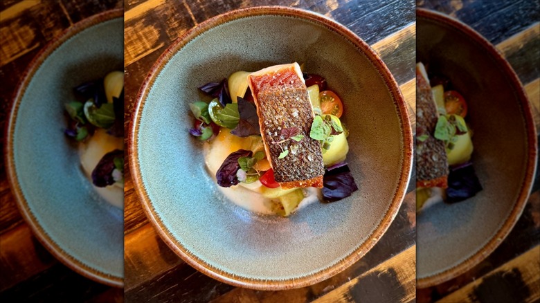 Salmon piece in a bowl of sauce and greens