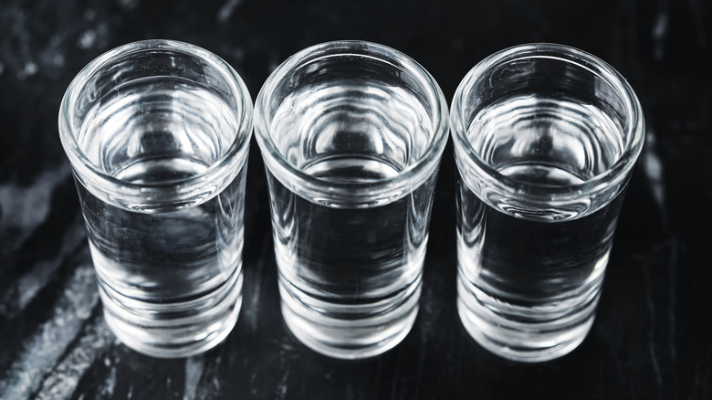 Three shots of vodka on black background