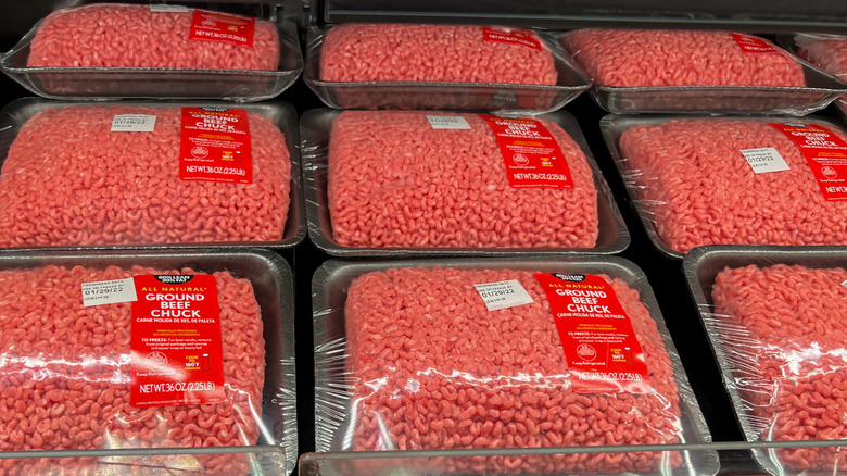 A grocery store ground beef section with several packages of ground beef chuck for sale