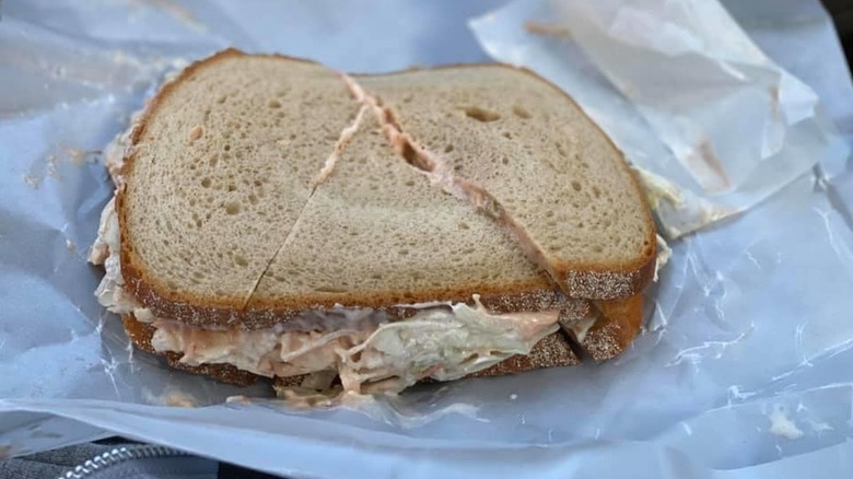 Millburn Deli cold sandwich sloppy joe on rye bread slices with mayo and veggies on wax paper
