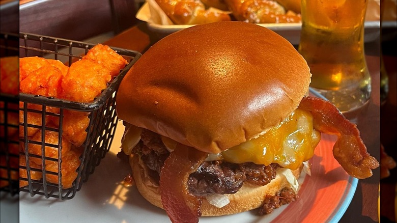 Sloppy Joe's sloppy joe with added cheese and bacon with side of tater tots in wire basket