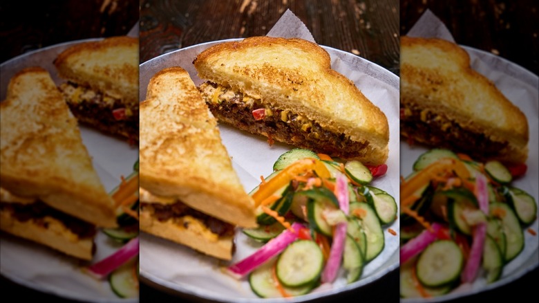 The Southern General Sloppy Joe on toasted sliced bread cut in half with veggies on side