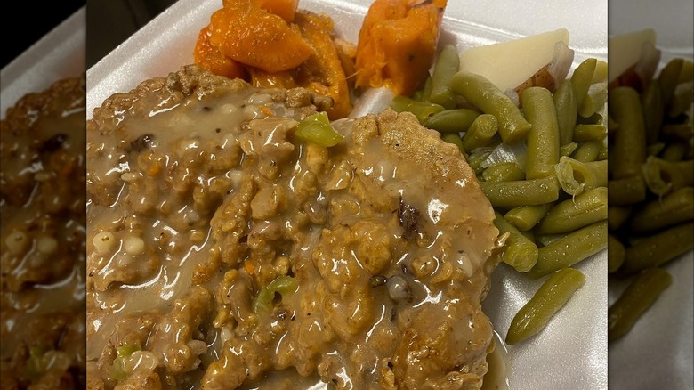 Mrs. White's Golden Rule Cafe fried chicken and greens with carrots in styrofoam takeout container