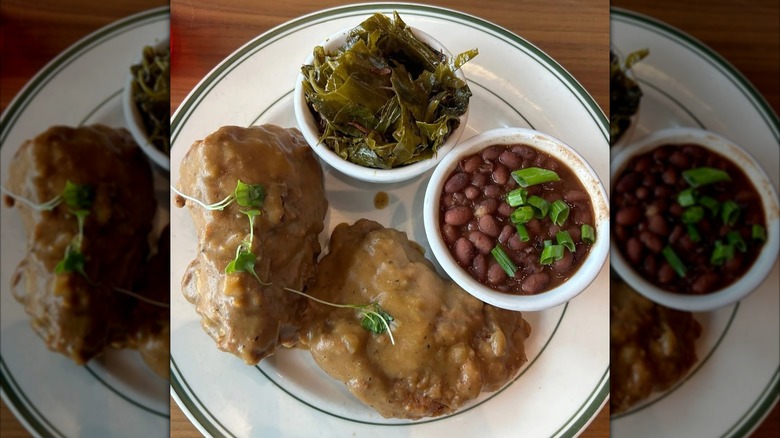 Fixins Soul Kitchen fried chicken smother in gravy next to side of collard greens and red beans