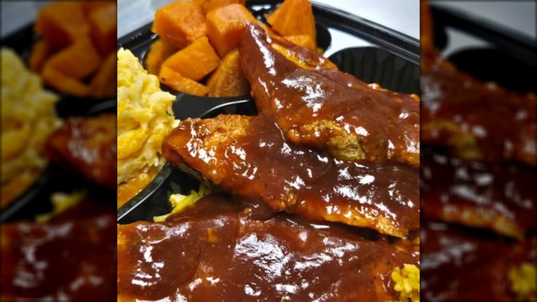 Tomeka's Homestyle Eatery fried catfish smother in barbecue sauce with sides in plastic container