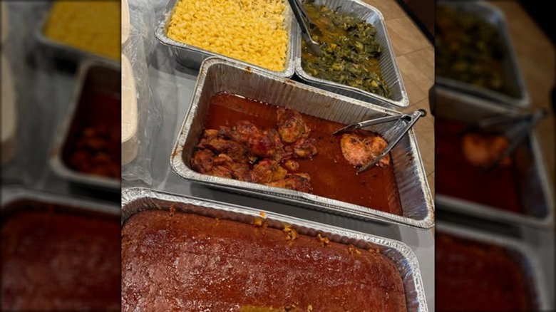 soul food in aluminum warming trays like chicken, mac and cheese, cake, and greens