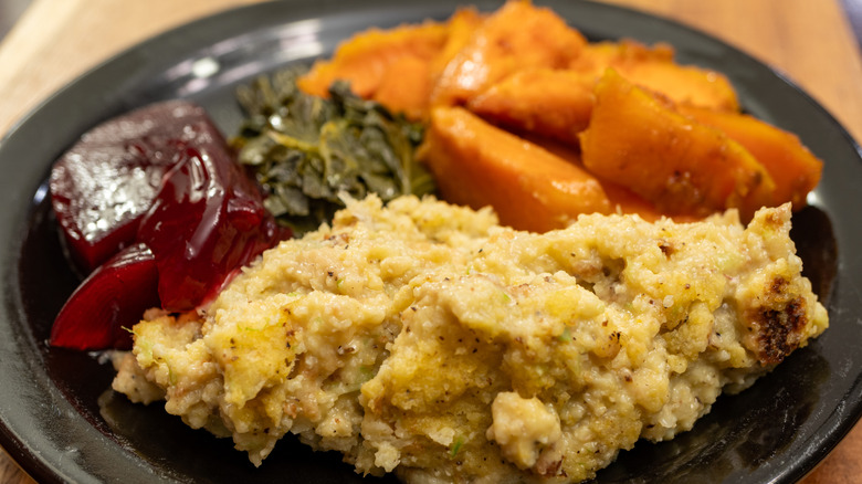 Plate of stuffing, cranberry sauce, yams, and collard greens