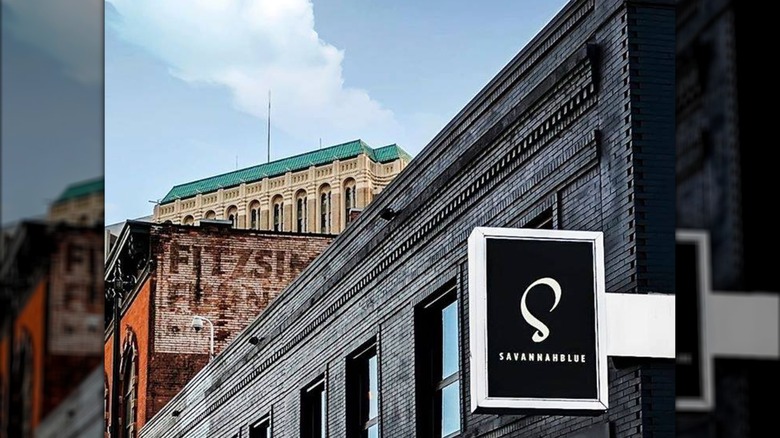 Brown brick storefront of SavannahBlue with small white and black restaurant sign