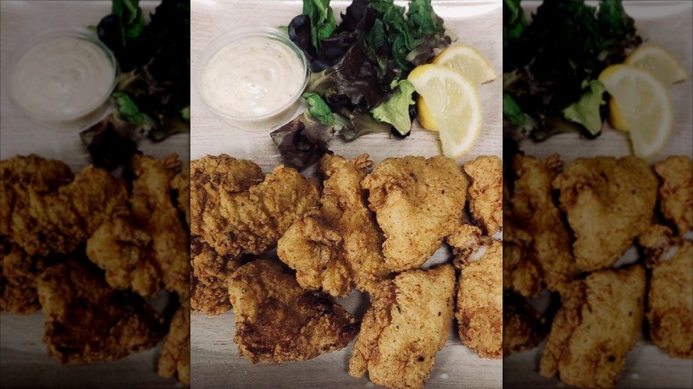 Zanzibar Soul Fusion fried chicken, salad greens, lemon, and side of dressing on plate