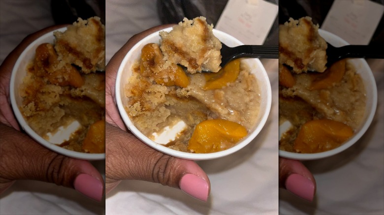 Spoon scooping peach cobbler out of a cup