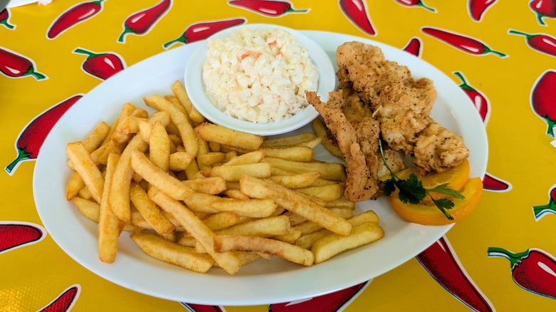 Southern Kitchen fried fish and fries with coleslaw on white plate on yellow chili pepper tablecloth