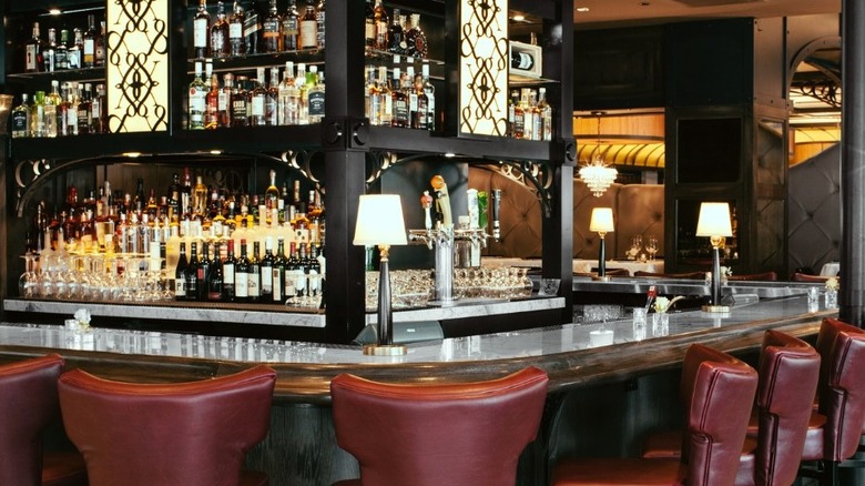 A view of the stocked bar at the restaurant with red leather high chairs and old-school decor
