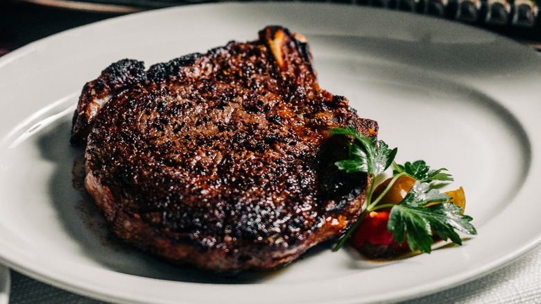 Perfectly charred pepper crusted steak served on a white plate with garnish