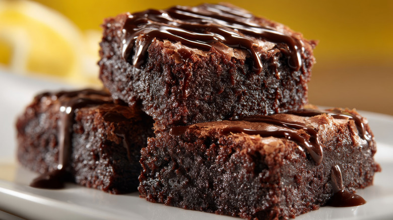 Three tender brownies with chocolate drizzle on them.