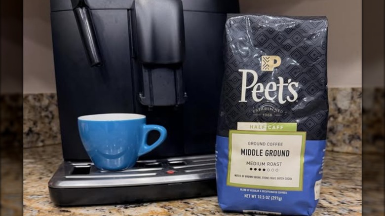 A coffee maker, a blue mug, and a bag of Peet's coffee positioned on a kitchen counter