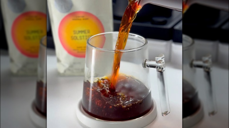 Coffee being poured into a glass. A bag of coffee is next to the glass