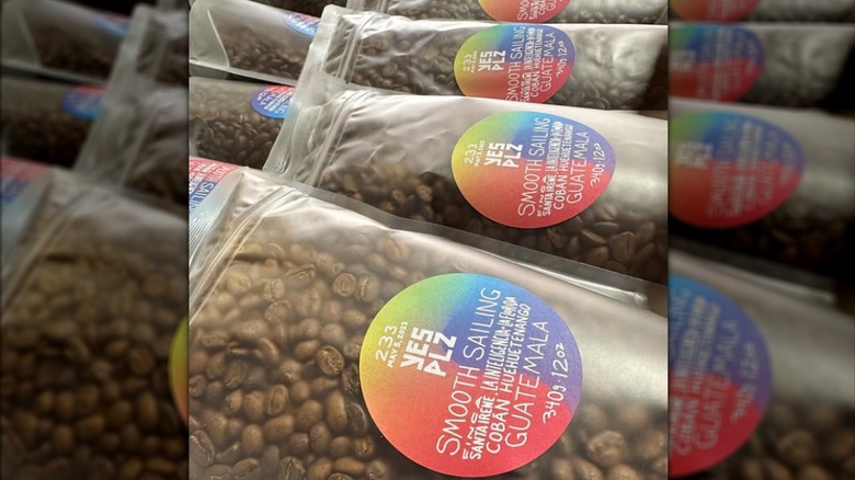 A few clear, plastic Yes Plz bags of coffee lying in rows