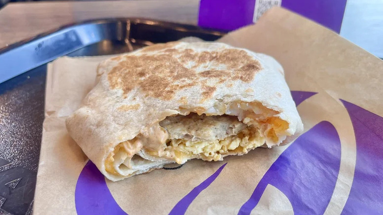 Taco Bell Breakfast Crunchwrap with Sausage bitten into revealing interior.