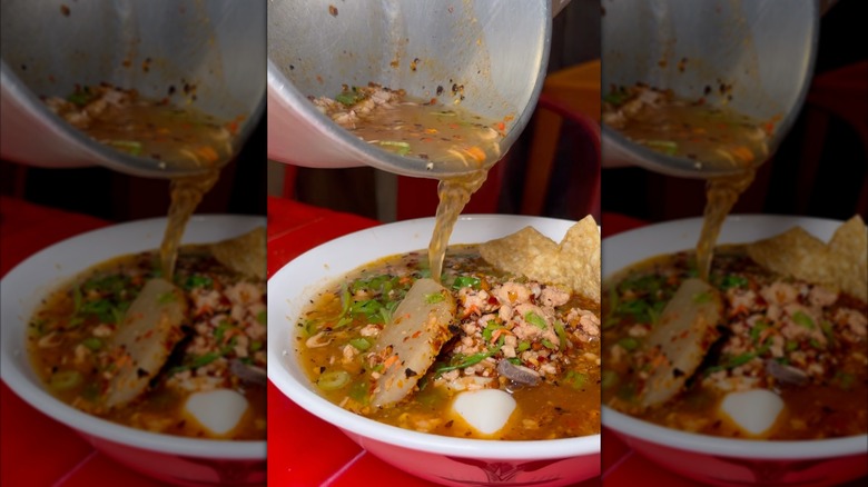 Hot broth poured from saucepan into bowl of Thai dish at Noodles Party restaurant