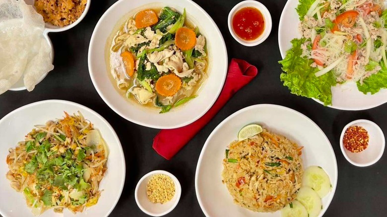 Various Thai dishes including rice, noodles, and a soup arranged on a table from All Thai'd Up restaurant