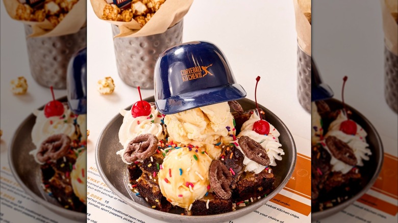 Curveball Kitchen ice cream scoops in a bowl with a toy size baseball cap placed on top