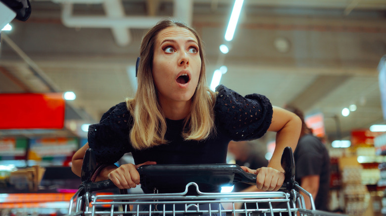 A woman shopping at a grocery store looking surprised at something off screen.