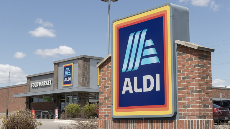 The exterior of an Aldi location with a glowing Aldi sign at night.