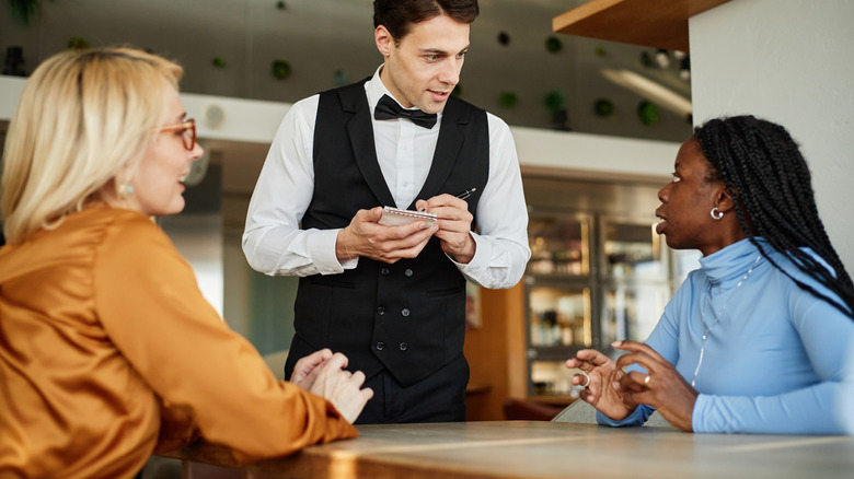 Women engaging in conversation with a waiter