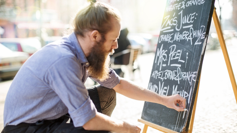Chef writing daily specials on a chalkboard outside of a restaurant