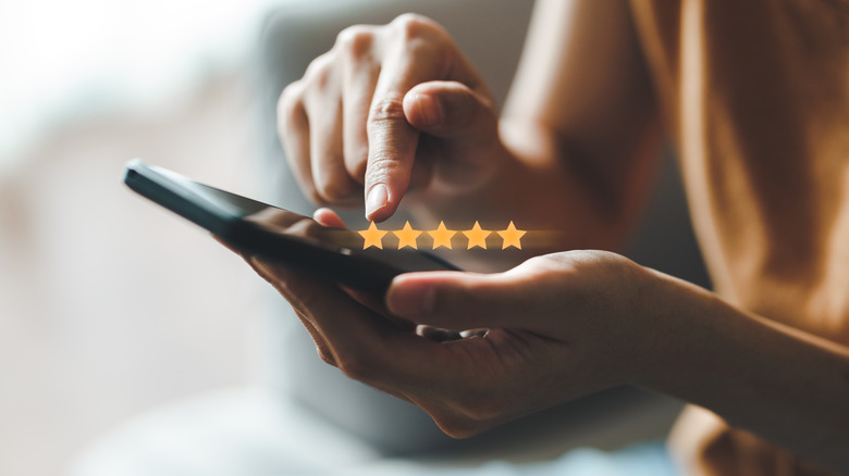 Close up of a person looking at a phone with five stars indicating a positive review