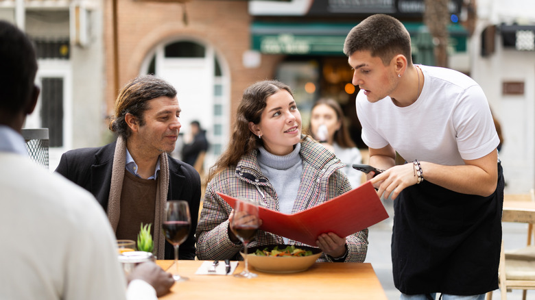 People ordering a meal from a waiter at an al fresco restaurant