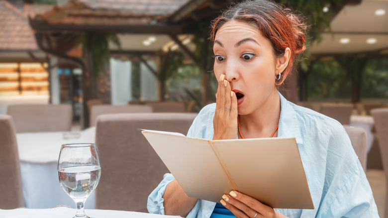Woman looking surprised while holding a menu