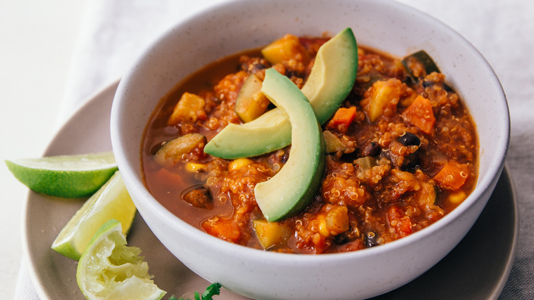 Bowl of vegan chili with avocado slices and lime edges