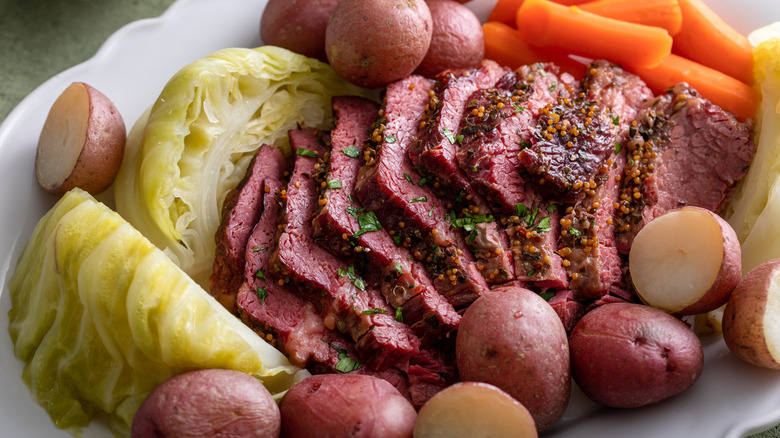 Sliced corned beef with roasted vegetables on a plate