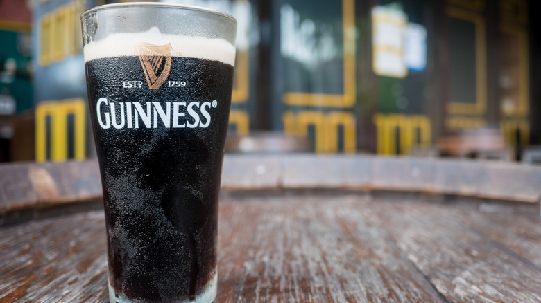 A pint of dark beer in a Guinness branded glass