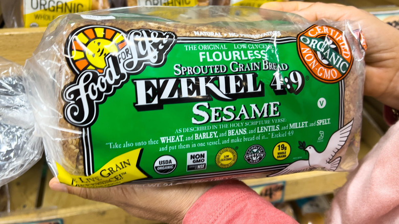 A person's hands hold a loaf of Ezekiel 4:9 Sprouted Grain Bread in Sesame flavor