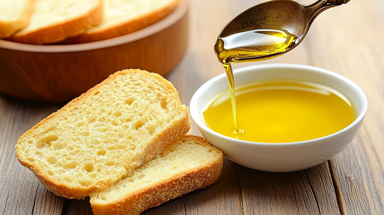 Pieces of crusty bread about to be covered in dipping oil from a white bowl