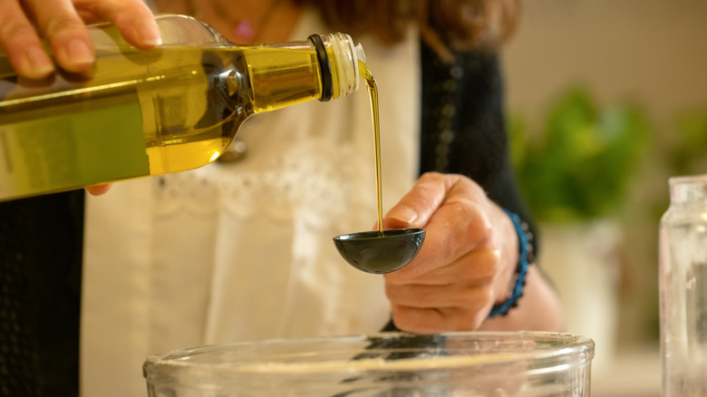 A baker measuring out olive oil.