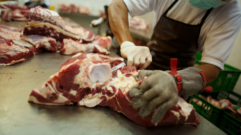 A person butchering a side of beef into cuts