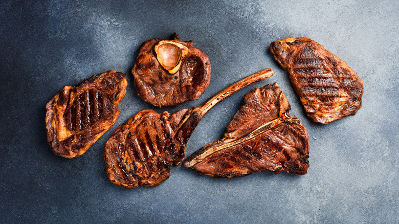 An array of different steak cuts cooked on a gray background