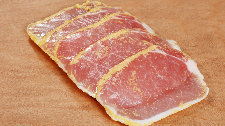 Slices of cornmeal coated peameal bacon on brown surface