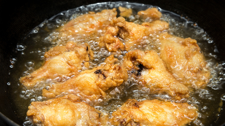 Chicken wings frying in a pan.
