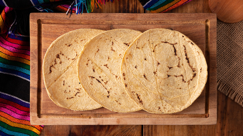 Three corn tortillas on a wooden board