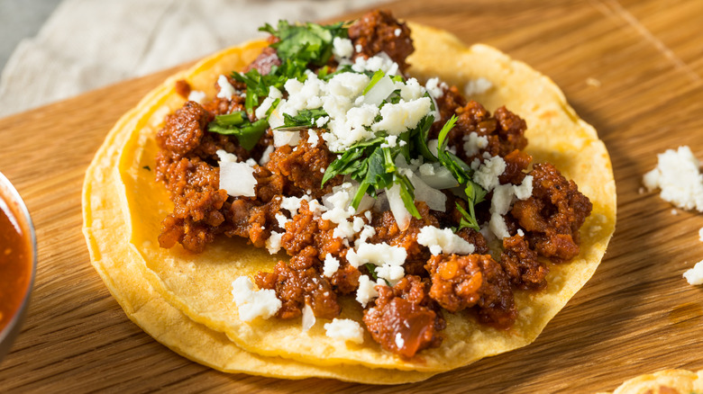 Tacos made with corn tortillas and chorizo and topped with cheese and herbs