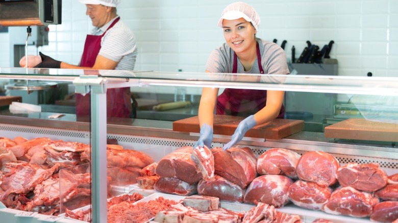 Two employees behind the counter of a butcher shop.
