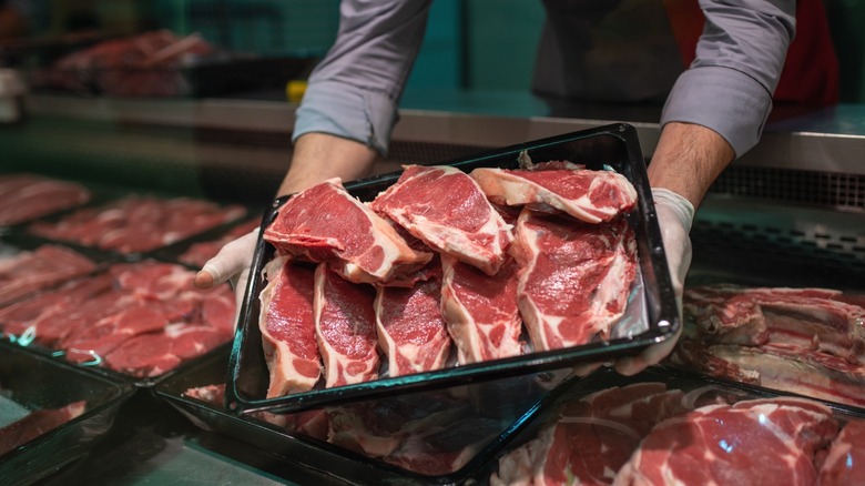 A butcher holding a tray of meat.