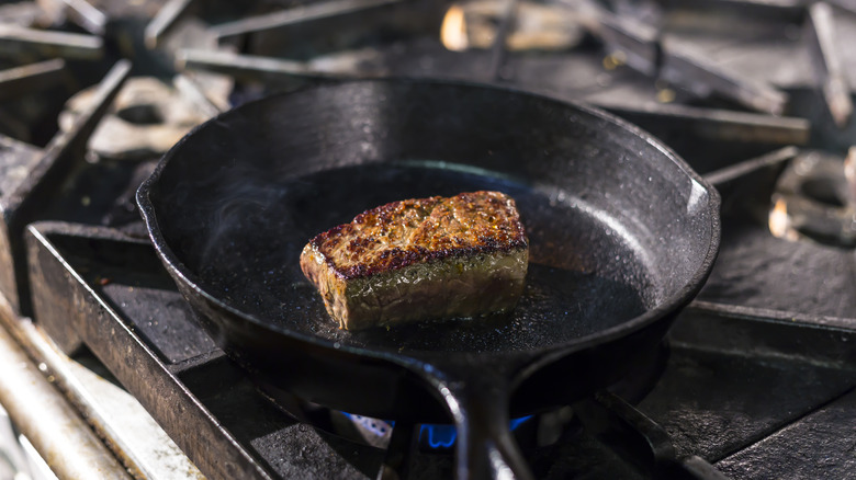 steak cooking in a black frying pan