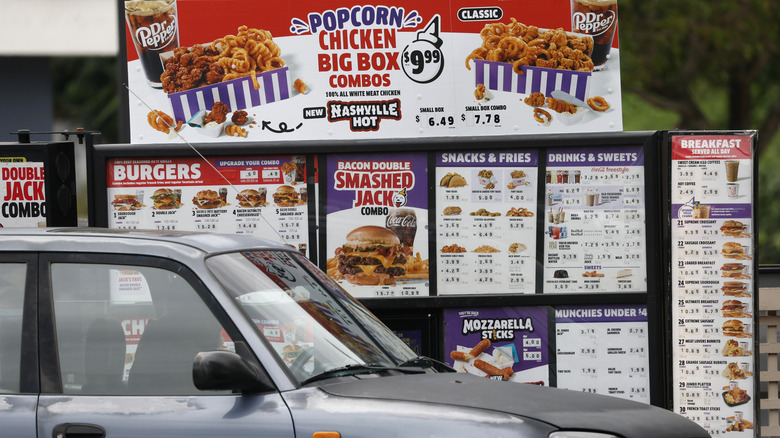 Someone in a vehicle ordering at a Jack in the Box drive-thru window.